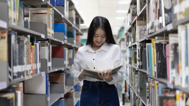 A girl holding a book in the library - lmshero